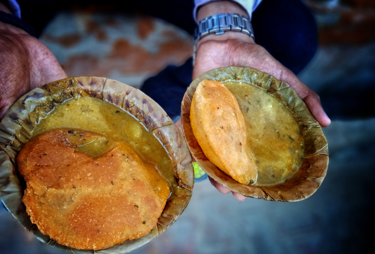 Traditional Varanasi vegetarian dishes including kachori, sabzi, and sweets served on a steel plate
